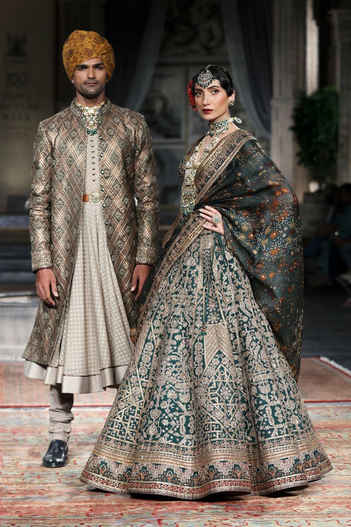 Models showcase intricate traditional attire on the runway, highlighting elegant fashion design.